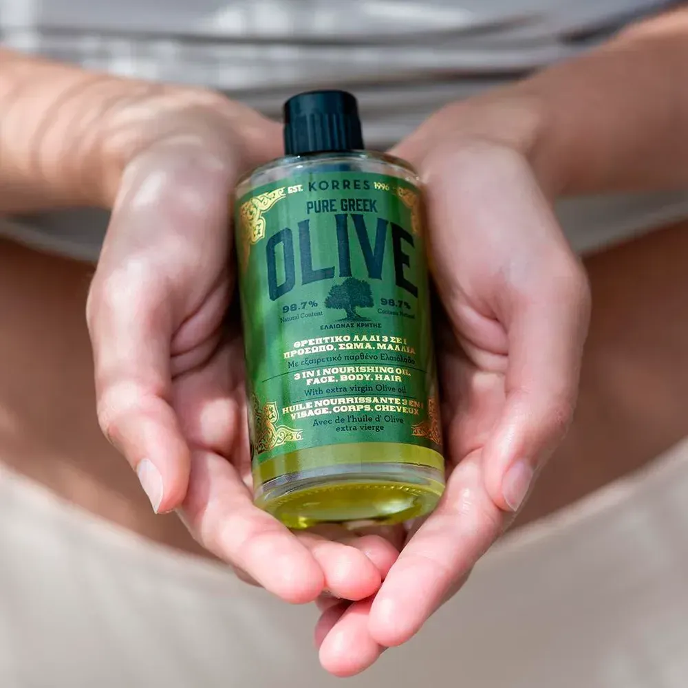 Mãos segurando o óleo nutritivo Pure Greek Olive